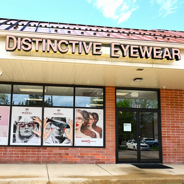 Exterior view of an eyewear store with branded signage and large promotional window displays.