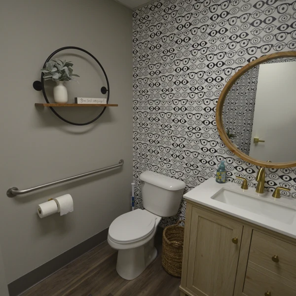 Clean, modern restroom with eye‑pattern wallpaper and minimalist décor accents.