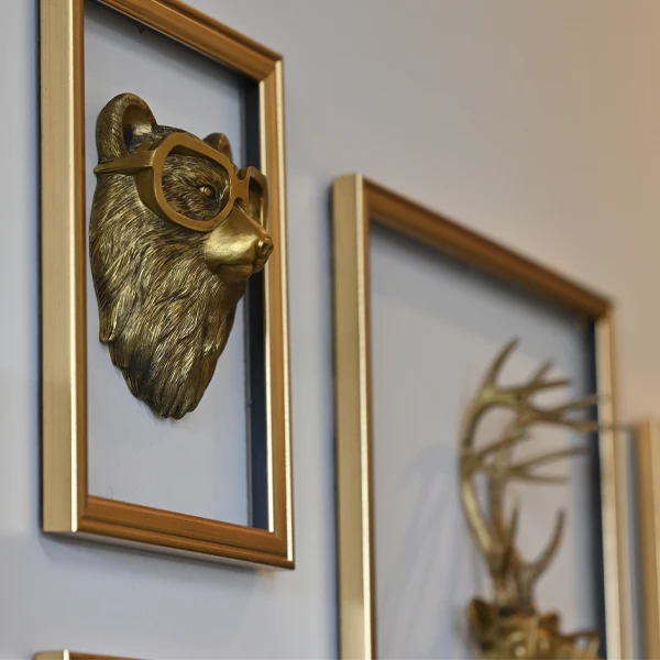 Decorative wall art featuring gold animal sculptures wearing eyeglasses in stylish frames.
